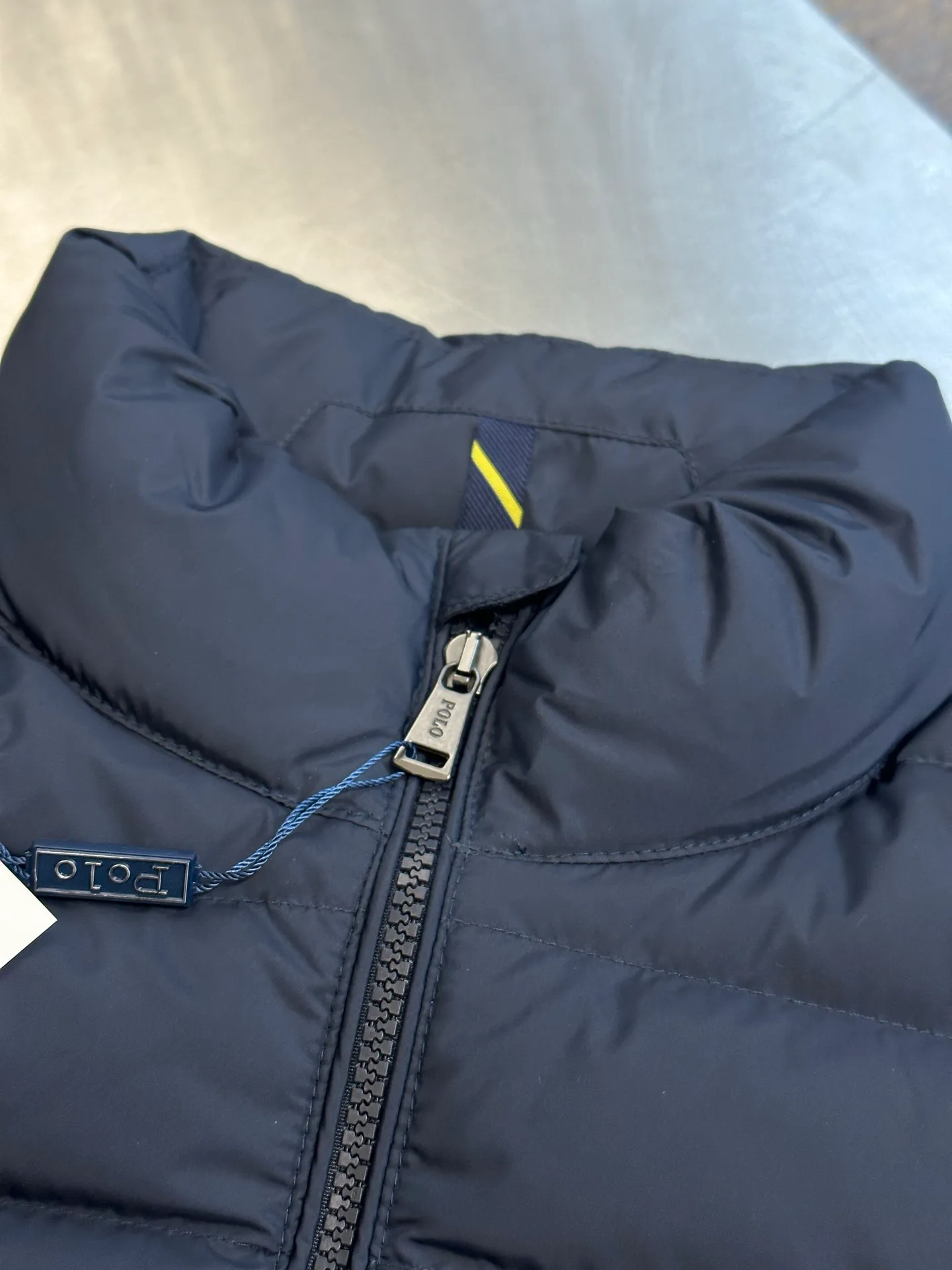P890 Ralph Lauren lightweight down jacket. The nylon fabric has good windproof and waterproof properties, which can effectively block the intrusion of wind and rain from the outside and keep the inside dry. It is suitable for wearing in humid or rainy environments. The red label on the chest is made with an imported MECLO embroidery machine. The original pattern is scanned first, and then high-quality silk thread is used to make a pattern. The density effect is adjusted by continuous pattern making.  The zipper design is simple and elegant, easy to operate, and the closing design of the cuffs and hem effectively prevents cold wind from invading, improving the warmth and comfort of wearing. It uses 90 white duck down with a weight of 260g to ensure excellent thermal insulation performance. After strict screening and processing, the velvet is not easy to drill, ensuring durability. size: s m l xl